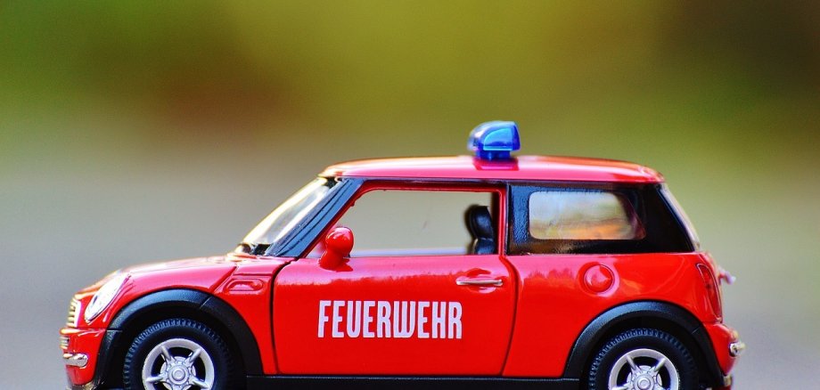 Ein kleines Feuerwehr Spielzeugauto, auf einer Straße.