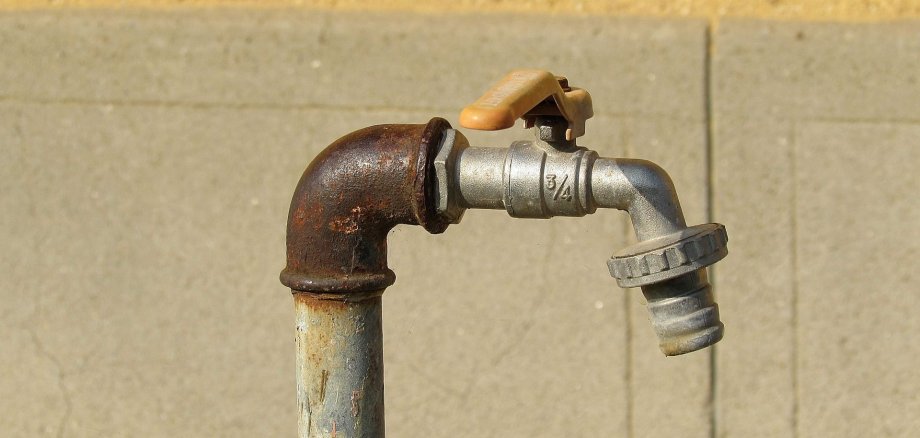 Ein öffentlicher Wasserhahn, welcher oben im knick gerostet ist.